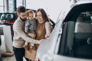 Kostenloses Foto familie mit baby, die ein auto in einem autosalon wählt