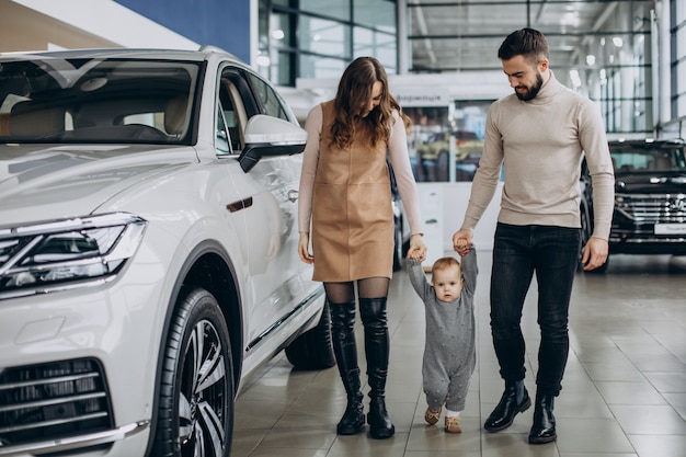 Familie mit Baby, die ein Auto in einem Autosalon wählt