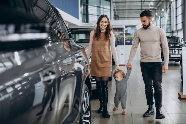 Kostenloses Foto familie mit baby, die ein auto in einem autosalon wählt