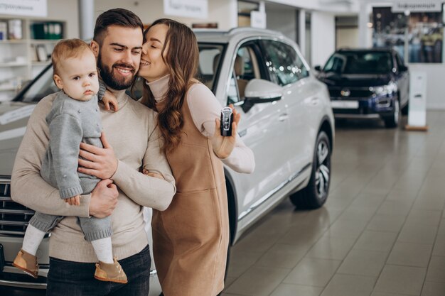 Familie mit bbay-Mädchen, das ein Auto in einem Autosalon wählt