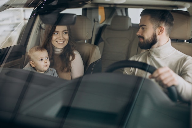 Familie mit bbay-mädchen, das ein auto in einem autosalon wählt