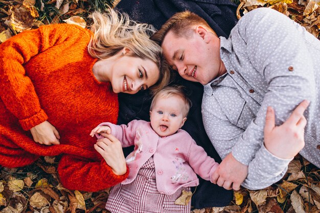 Familie mit dem Baby daugher, das auf Blättern im Park liegt