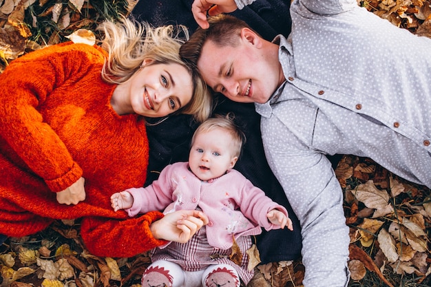 Familie mit dem Baby daugher, das auf Blättern im Park liegt