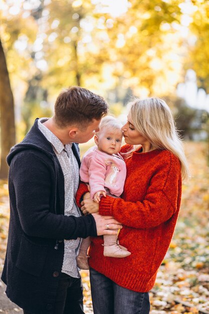 Familie mit dem Baby daugher, das in einen Herbstpark geht