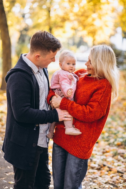 Familie mit dem Baby daugher, das in einen Herbstpark geht