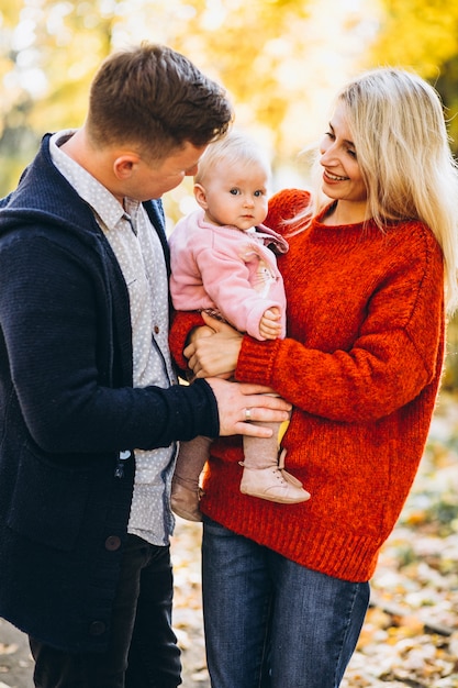 Familie mit dem Baby daugher, das in einen Herbstpark geht