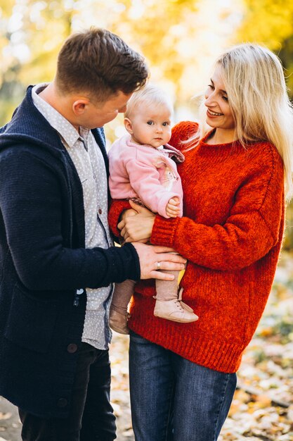 Familie mit dem Baby daugher, das in einen Herbstpark geht