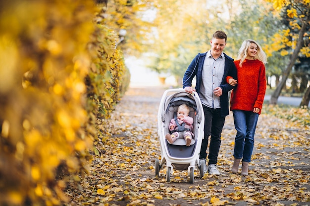Familie mit dem Baby daugher, das in einen Herbstpark geht