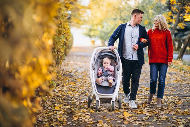 Familie mit dem Baby daugher, das in einen Herbstpark geht