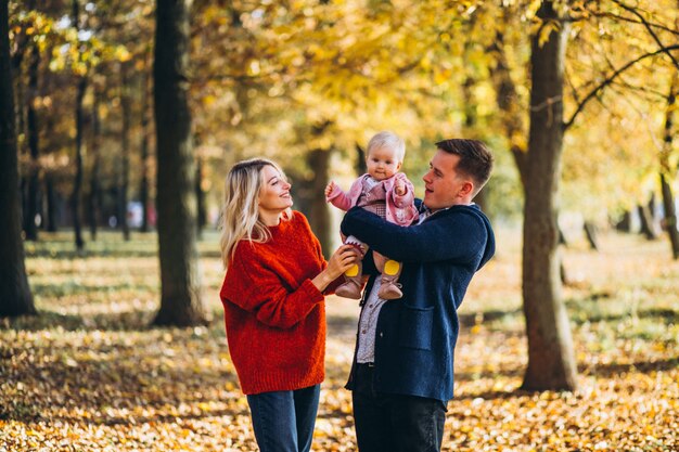 Familie mit dem Baby daugher, das in einen Herbstpark geht