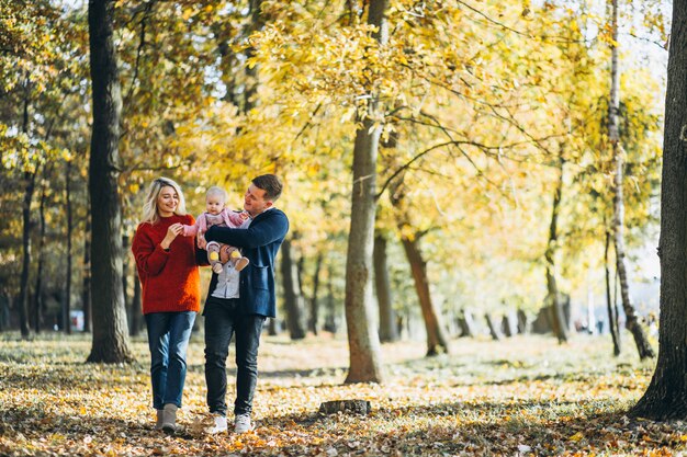 Familie mit dem Baby daugher, das in einen Herbstpark geht