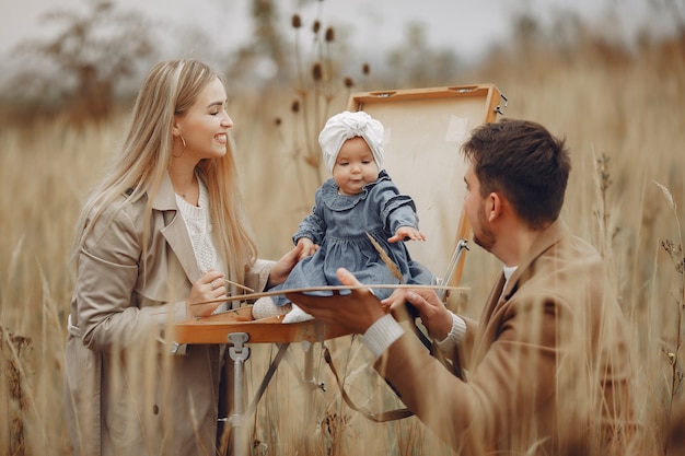 Familie mit der kleinen Tochter, die in einem Herbstfeld malt