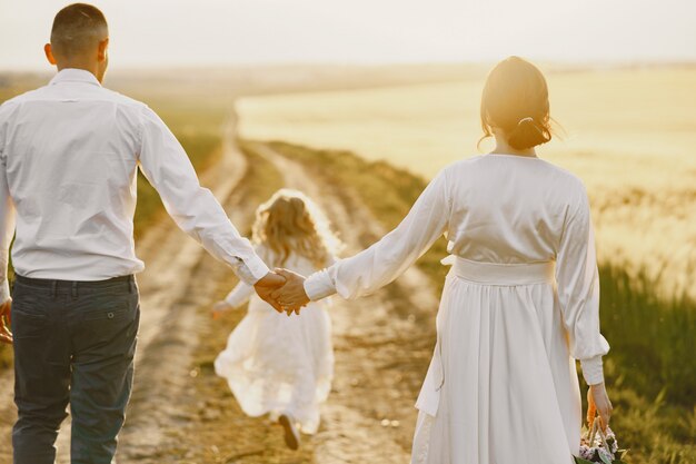 Familie mit der kleinen Tochter, die Zeit zusammen im sonnigen Feld verbringt