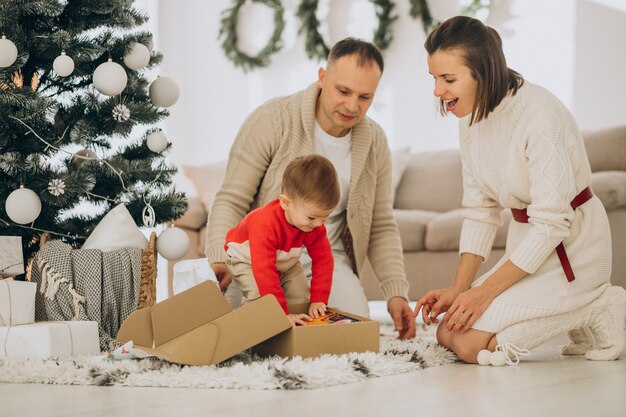 Familie mit kleinem Sohn an Weihnachten durch Weihnachtsbaum zu Hause