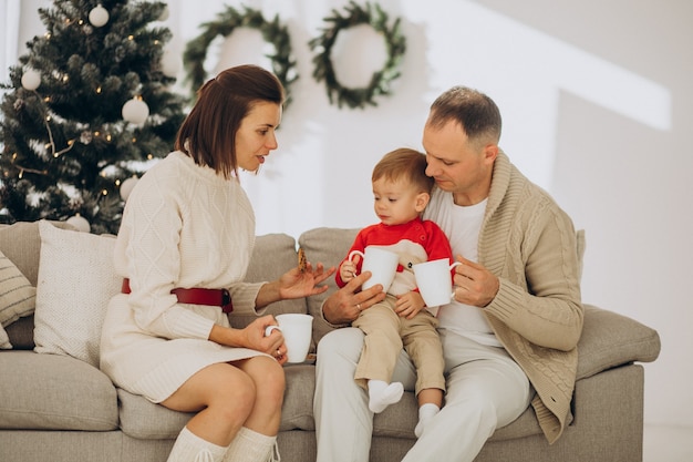 Familie mit kleinem Sohn an Weihnachten durch Weihnachtsbaum zu Hause