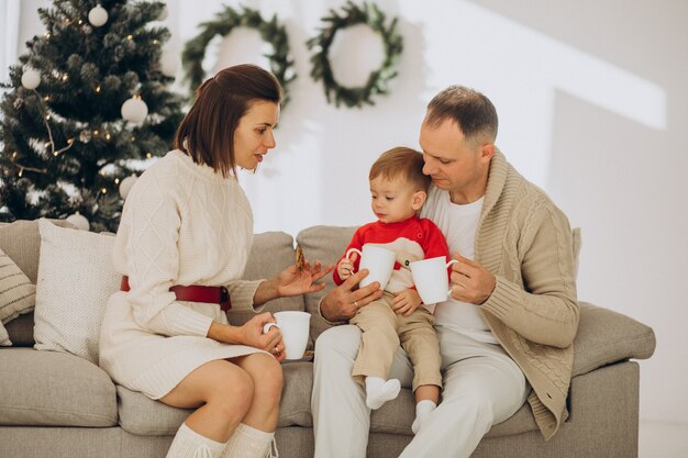 Familie mit kleinem Sohn an Weihnachten durch Weihnachtsbaum zu Hause