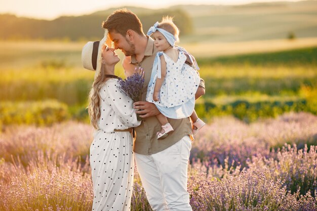 Familie mit kleiner Tochter auf Lavendelfeld. Schöne Frau und niedliches Baby, das im Wiesenfeld spielt. Familienurlaub im Sommertag.