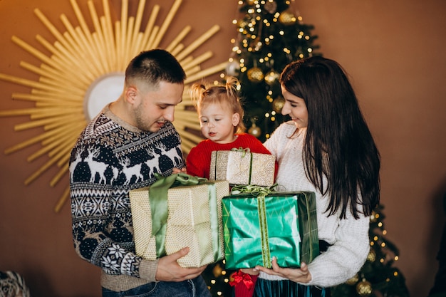 Familie mit kleiner Tochter durch den Weihnachtsbaum, der Geschenkbox auspackt