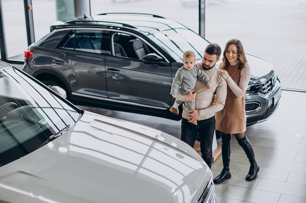 Familie mit Kleinkindmädchen, das ein Auto in einem Autohaus wählt