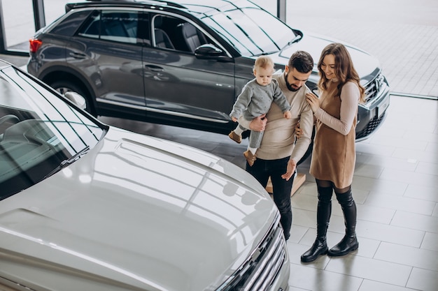 Familie mit Kleinkindmädchen, das ein Auto in einem Autohaus wählt