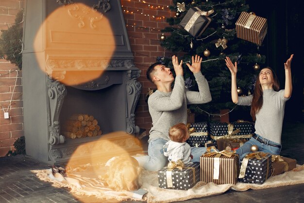 Familie mit niedlichem Hund zu Hause nahe Weihnachtsbaum