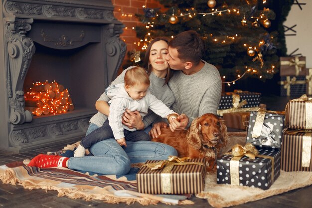 Familie mit niedlichem Hund zu Hause nahe Weihnachtsbaum