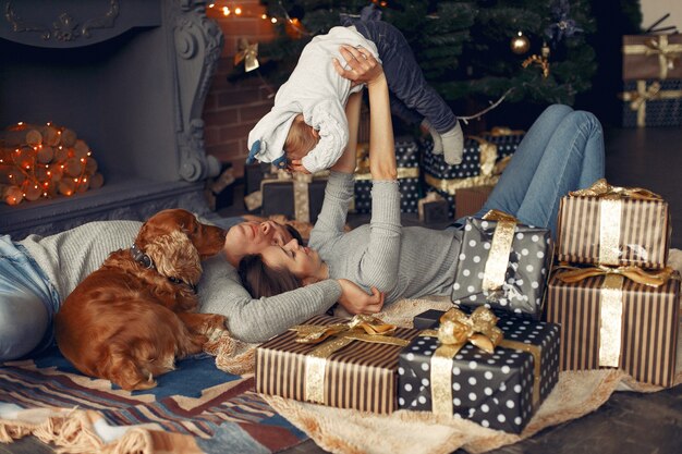 Familie mit niedlichem Hund zu Hause nahe Weihnachtsbaum