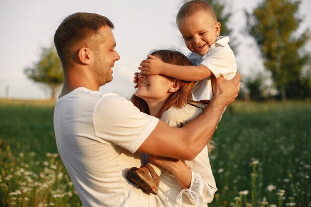 Familie mit niedlichem kleinen Kind. Vater in einem weißen T-Shirt. Sonnenuntergang Hintergrund.