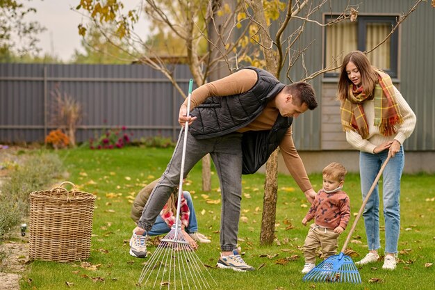 Familie mit Rechen, die Blätter im Garten säubert