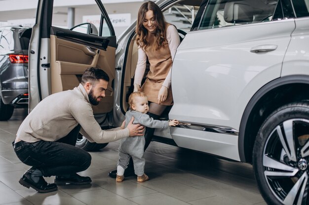 Familie mit süßer Tochter, die ein Auto in einem Autohaus wählt