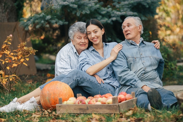 Familie sitzt in einem garten mit äpfeln und kürbis