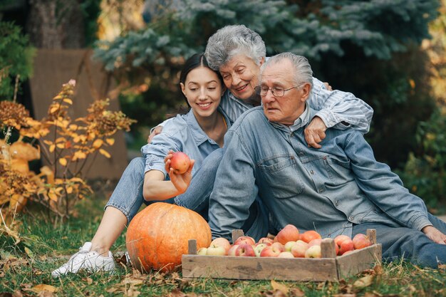 Familie sitzt in einem Garten mit Äpfeln und Kürbis