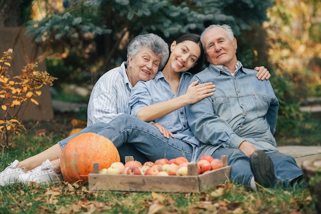 Familie sitzt in einem Garten mit Äpfeln und Kürbis