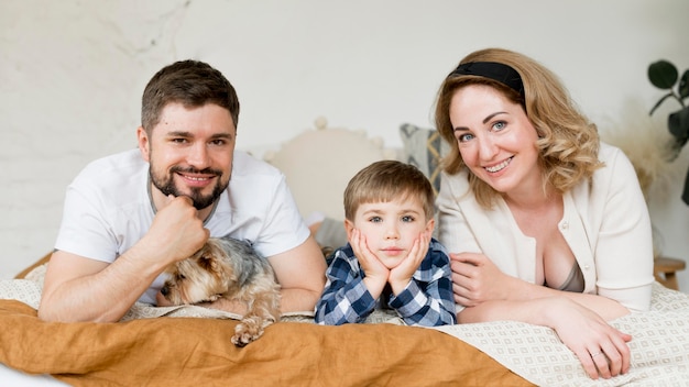 Familie sitzt mit ihrem hund auf dem bett