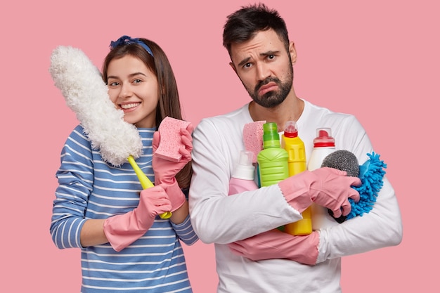 Familie teilen Hausarbeiten zusammen glückliche Dame trägt Schwamm zum Abwischen von Staub, weiße Bürste, hat Ausdruck erfreut