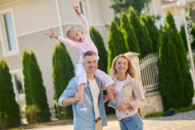Familie zu Fuß. Papa trägt ein Mädchen auf seinen Schultern beim Familienspaziergang