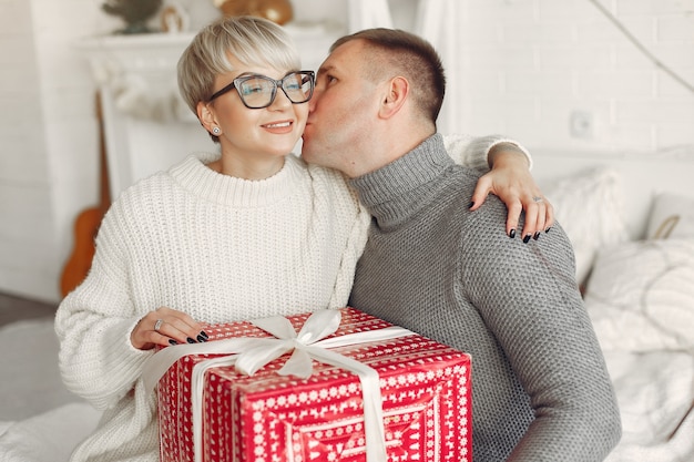 Familie zu Hause. Paar in der Nähe von Weihnachtsdekorationen. Frau in einem grauen Pullover.