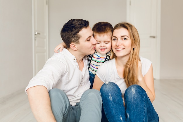 Familienbild von zwei jungen Eltern, die mit ihrem Jungenkind spielen