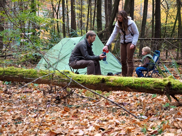 Familiencamping mit einem Zelt in einem Wald, umgeben von Bäumen und Blättern im Herbst