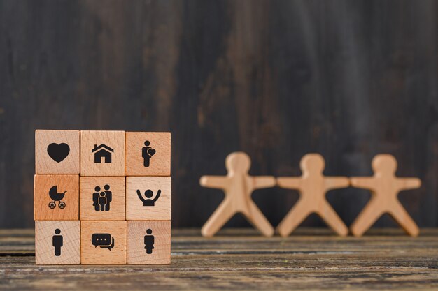 Familienkonzept mit Ikonen auf Holzwürfeln, menschliche Figuren auf Holztischseitenansicht.
