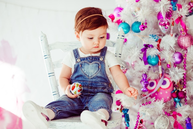 Fantasie gekleidetes kleines Mädchen betrachtet etwas auf Weihnachtsbaum