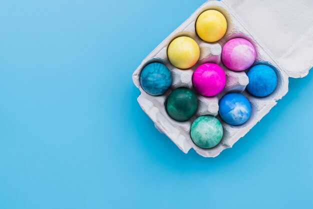 Farbige Eier im Kartongestell auf blauem Hintergrund