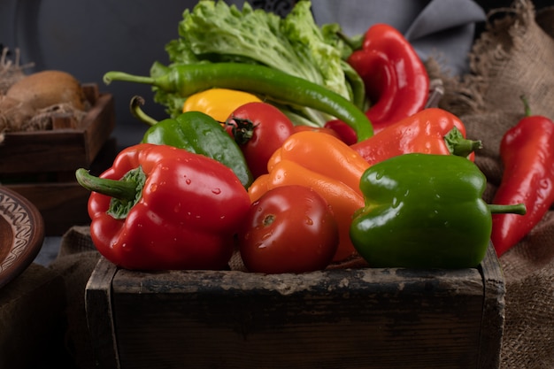 Farbige Paprika in einem rustikalen Behälter.