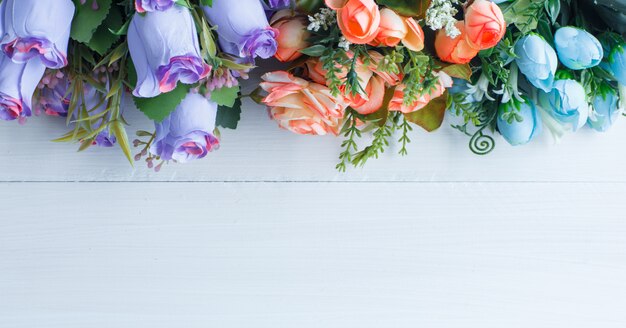 Farbige Rosen mit Zweigen auf weißem hölzernem Hintergrund, flache Lage.