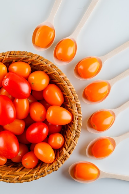 Farbige Tomaten in Holzlöffeln und Korb Draufsicht