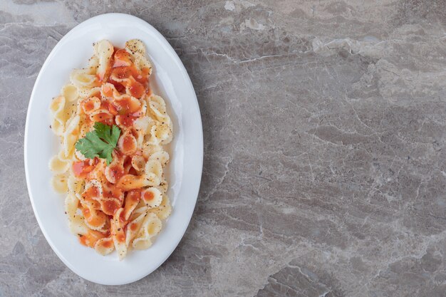 Farfalle-Nudeln mit Bolognese auf dem Teller, auf der Marmoroberfläche.