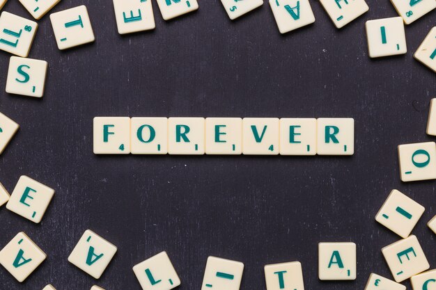 Fassen Sie für immer in scrabble Buchstaben über schwarzem Hintergrund ab