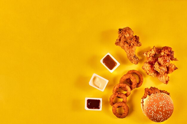 Fast-Food- und ungesundes Ernährungskonzept - Nahaufnahme von Fast-Food-Snacks auf gelbem Hintergrund. Ansicht von oben. Platz kopieren. Stillleben. Flach liegen.