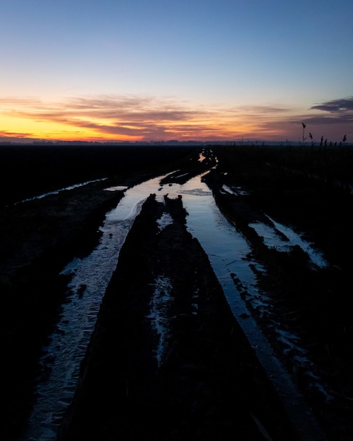 Faszinierende Ansicht des gefrorenen Bodens im Feld während des Sonnenuntergangs