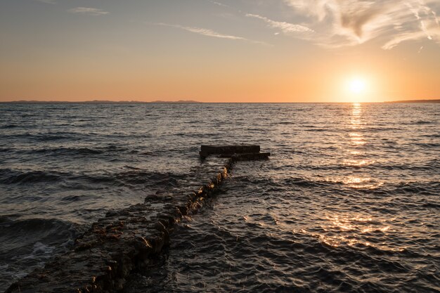 Faszinierende Ansicht des Ozeans und eines Piers unter buntem Himmel während des Sonnenuntergangs in Dalmatien, Kroatien